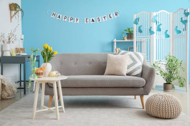 Interior of living room with Easter decor, sofa and tables