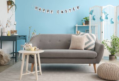Interior of living room with sofa, workplace and Easter decor