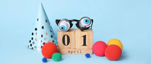Calendar and party decor for April Fools\' Day on light blue background