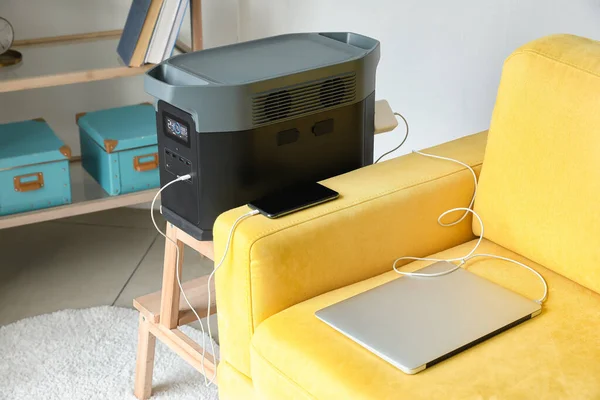 Portable power station charging gadgets on stool in living room
