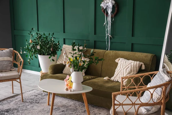 Interior of living room with green sofa, plants and Easter eggs