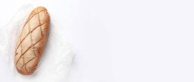 Baking paper with loaf of fresh bread on white background with space for text