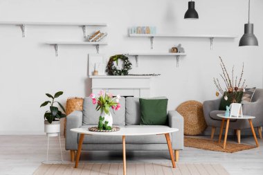 Interior of living room decorated for Easter celebration with tulips in vase and sofa