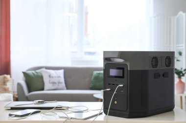 Portable power station charging gadgets on table in living room