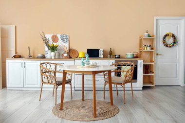 Interior of stylish kitchen with Easter decor, white counters and dining table