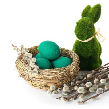 Nest with Easter eggs, rabbit and willow branches on white background