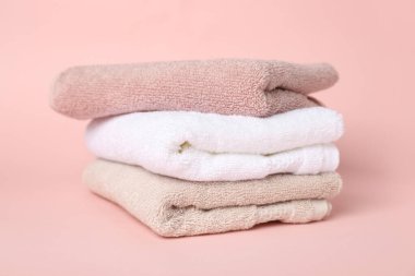 Stack of clean towels on pink background