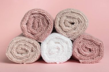 Rolled clean towels on pink background