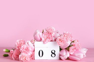 Cube calendar with date MARCH 8 and beautiful flowers on pink table. Women's Day celebration