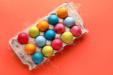 Cardboard holder with painted Easter eggs on color background