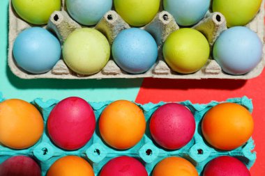 Cardboard holders with painted Easter eggs on color background, closeup