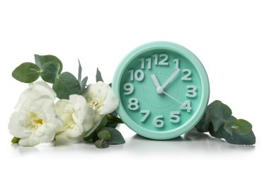 Alarm clock with beautiful freesia flowers and eucalyptus branches on white background
