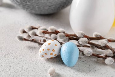 Easter eggs and willow branches on light background, closeup