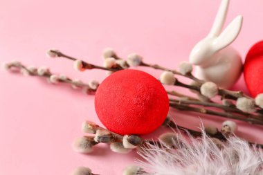 Painted Easter eggs and willow branches on pink background, closeup