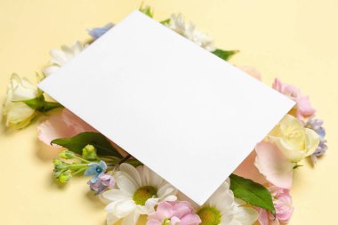 Composition with spring flowers and blank card on color background, closeup