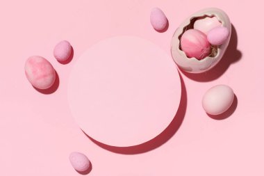 Blank greeting card and Easter eggs on pink background