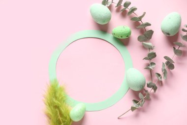 Round frame, Easter eggs, feather and eucalyptus branches on pink background