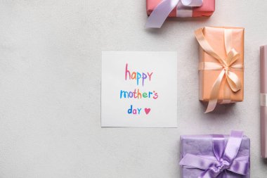 Card with text HAPPY MOTHER'S DAY and gift boxes on light background