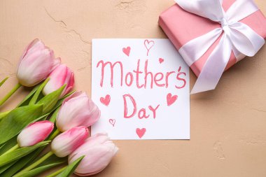 Card with text MOTHER'S DAY, beautiful tulip flowers and gift box on color background