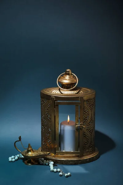 Muslim lantern with burning candle, lamp and prayer beads for Ramadan on dark background