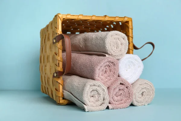 Basket with rolled clean rolled towels on color background