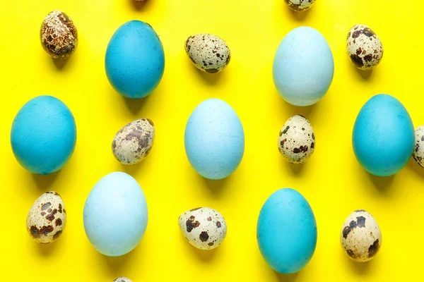 Painted and natural Easter eggs on yellow background