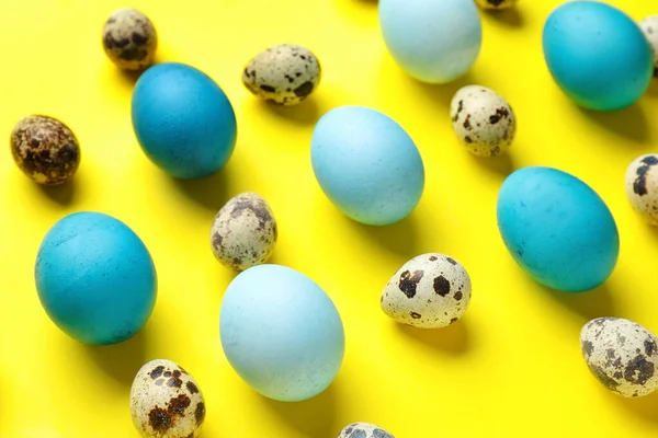 Painted and natural Easter eggs on yellow background, closeup