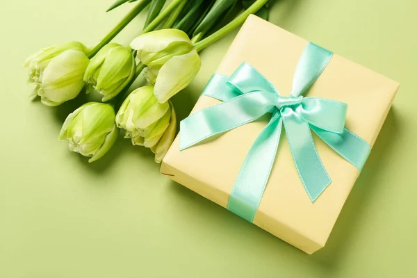 Gift and tulips on green background. Hello spring