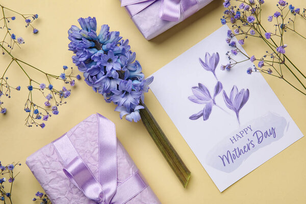 Композиция с поздравительными открытками, красивыми цветами и подарками для празднования Дня матери на цветном фоне