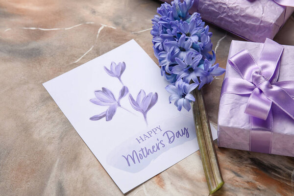 Карточка с текстом День Матери, подарочные коробки и красивый гиацинтовый цветок на фоне гранжа, крупным планом
