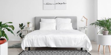 Big comfortable bed with clean linen in light hotel room