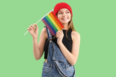 Beautiful young woman with LGBT flag on green background