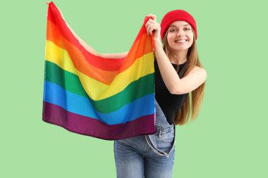 Beautiful young woman with LGBT flag on green background
