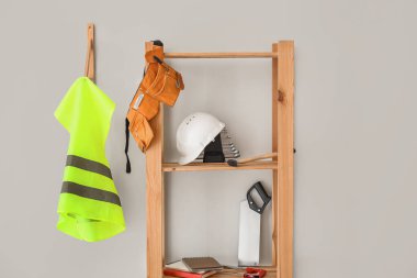 Shelving unit with builder's supplies and reflective vest on light wall