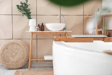 Interior of bathroom with modern bathtub, ceramic sink and laptop on board