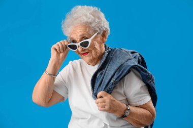 Senior woman in sunglasses on blue background