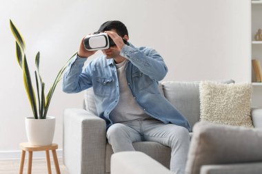 Young man using VR glasses at home