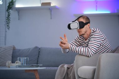 Young man using VR glasses at home