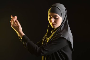 Praying Muslim woman on dark background