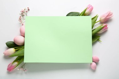Composition with blank card, flowers and Easter eggs on white background
