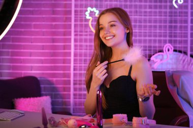 Female blogger with feather stick conducting sex education online at home