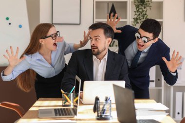 Colleagues with funny disguise and their boss in office. April Fools' Day celebration
