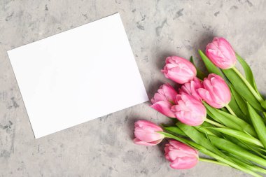 Beautiful tulip flowers and blank card on grey grunge background