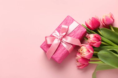 Gift box and beautiful tulip flowers on pink background. Hello spring