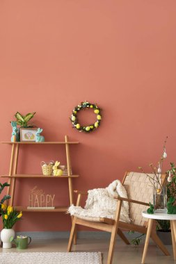 Interior of living room with Easter wreath, shelving unit and armchair