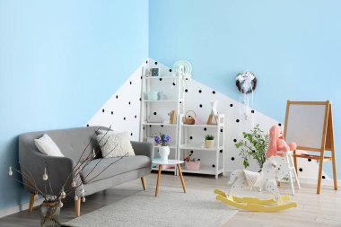 Interior of children's room with Easter wreath, shelving units and sofa