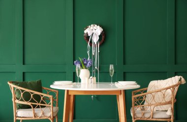 Interior of dining room with table and Easter wreath on green wall
