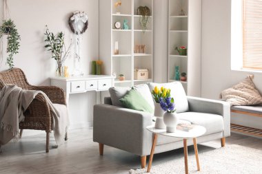 Interior of light living room with Easter wreath, sofa and shelving unit