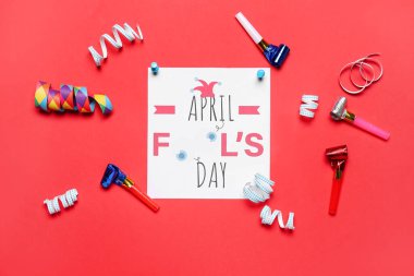 Card with text APRIL FOOL'S DAY, serpentine and whistles on red background