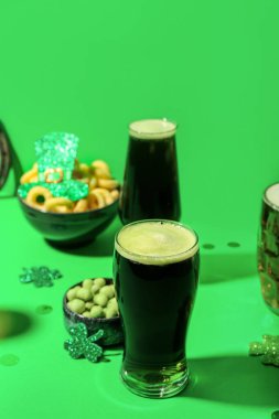 Glasses of beer, snacks and decor on green background. St. Patrick's Day celebration